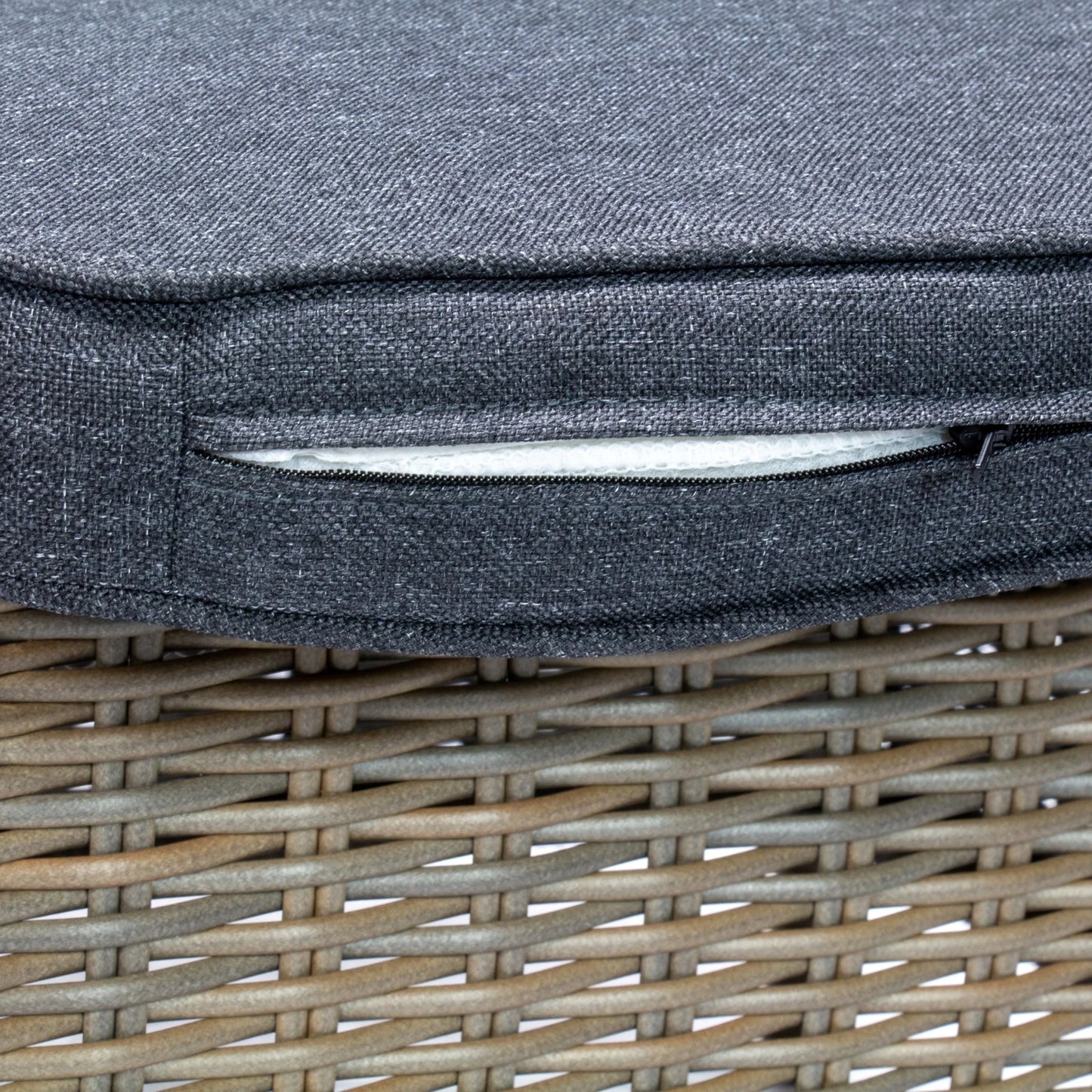 Close-up of grey cushion with visible zipper on a natural brown wicker rattan outdoor chair