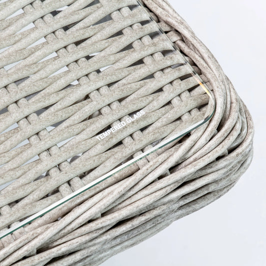 Close-up of grey poly rattan wicker outdoor furniture with a tempered glass tabletop