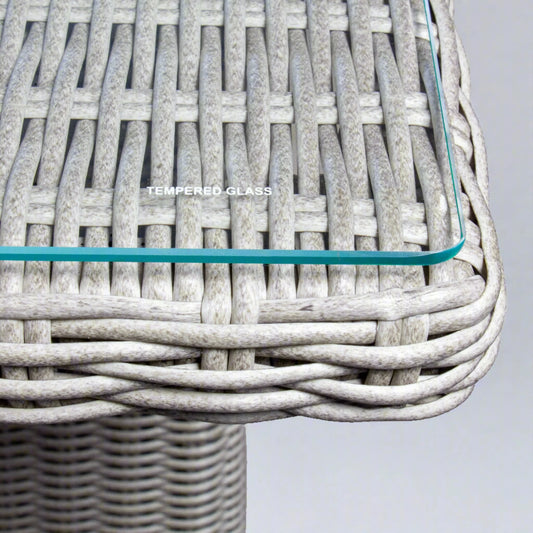 Grey poly rattan wicker outdoor table with tempered glass top, close-up detail view