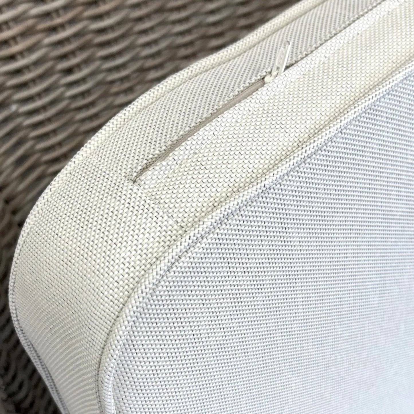 Close-up of outdoor rattan wicker furniture cushion with zipper, showcasing durable weave texture for patio use.