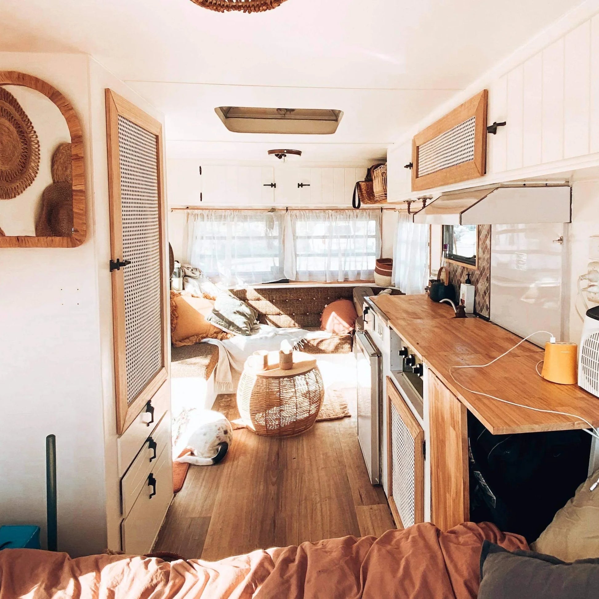 Boho RV interior with rattan furniture, cane webbing cabinets, and wicker decor for cozy tiny living